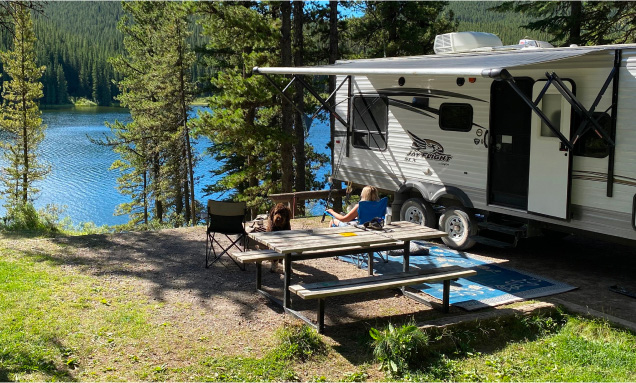 Travel trailer with its awning open parked lakeside