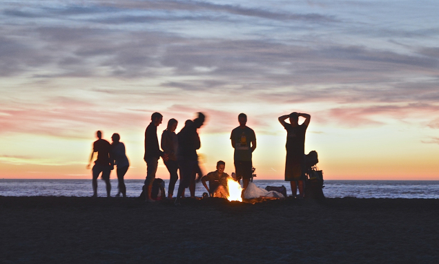 People having a bonfire on a lake at sunset