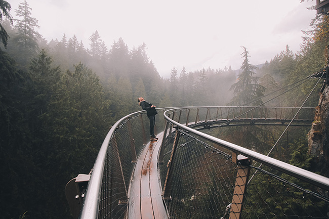 Man walking through dense forest on a suspended bridge