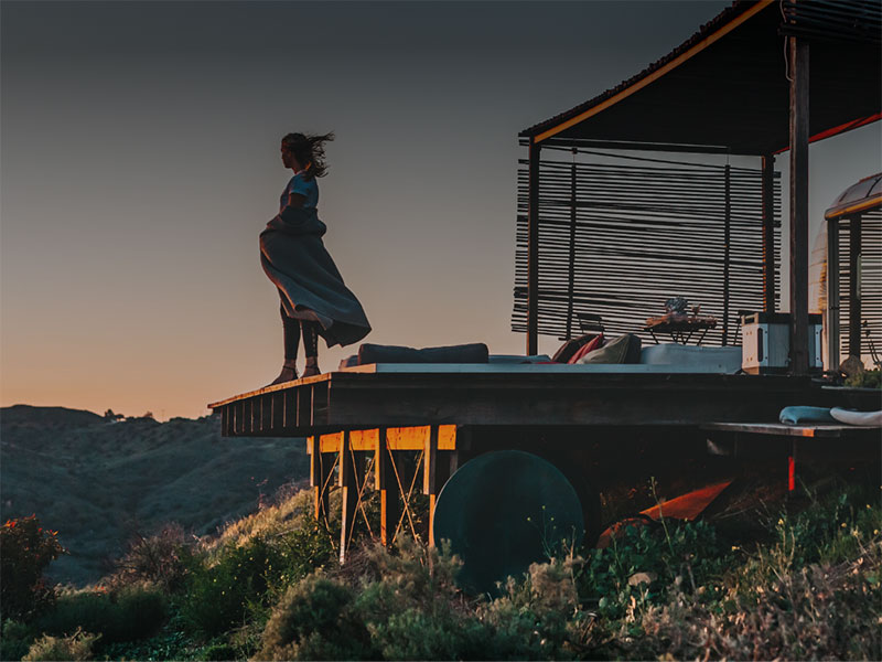 Une femme debout sur une terrasse regardant le coucher du soleil.