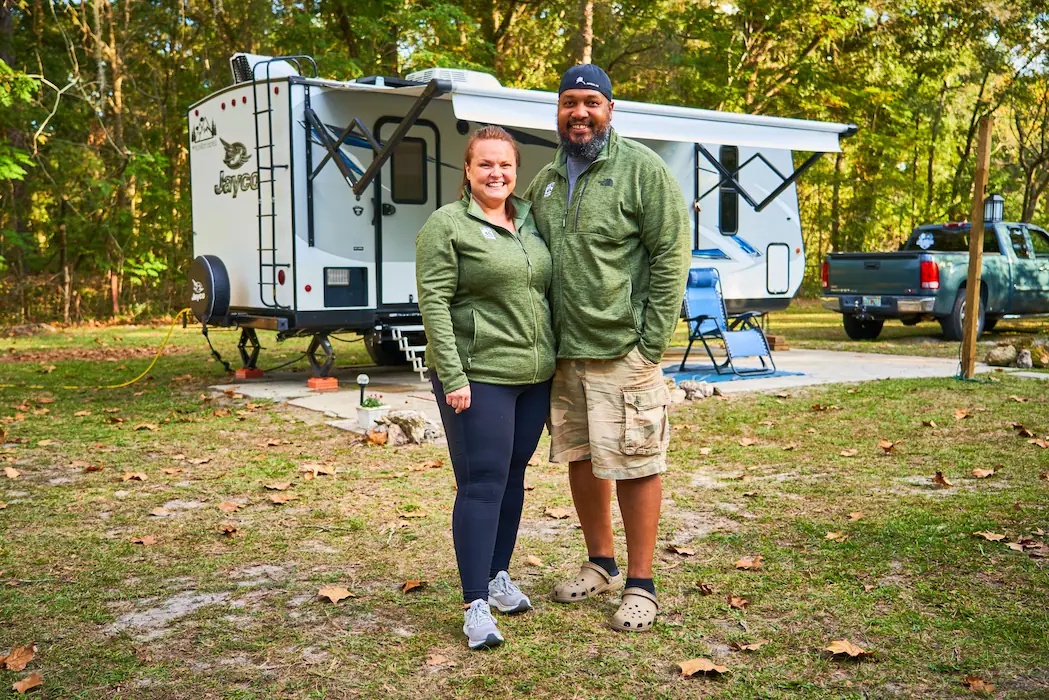 Happy RV owner with child beside a travel trailer, showing family-friendly RV rentals through RVezy