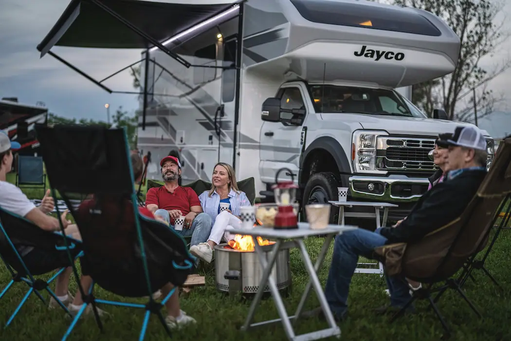 A family enjoying a camping setup with a Jayco RV, with a testimonial praising RVezy for their reliability and comprehensive coverage.