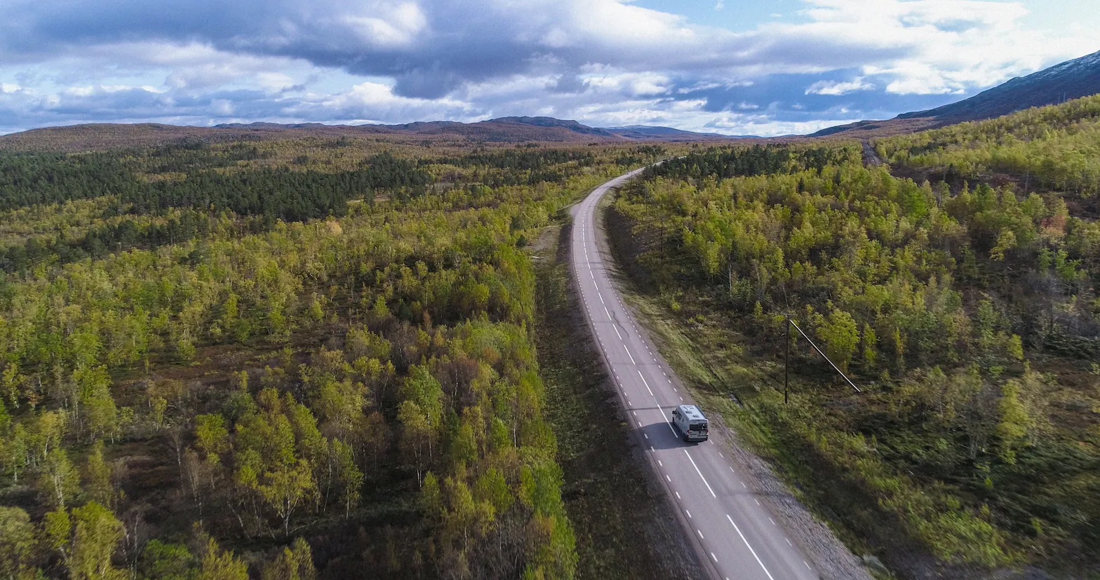 A motorhome driving through a scenic forest road, promoting how to rent your RV and earn extra income